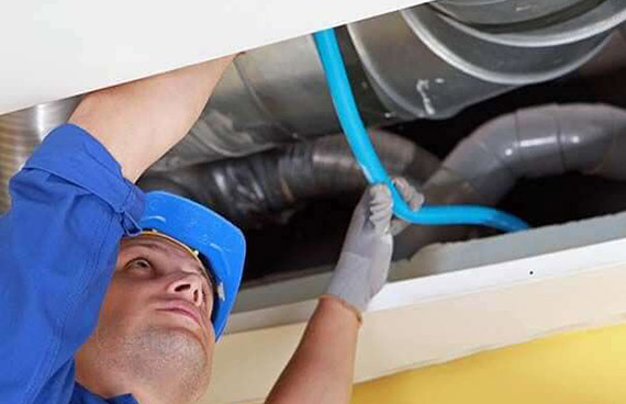 Air duct cleaning in Reston, VA, as service technician reaches into air duct system