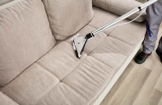 a worker vacuuming a couch providing Professional Residential Upholstery Cleaning in Leesburg, Virginia